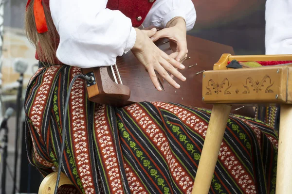 Una chica joven toca el instrumento de cuerda kokle — Foto de Stock