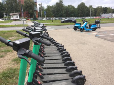 Avrupa, Letonya, Riga. Akıllı telefonları kullanan elektrikli scooterların ve scooterların park ve kiralanması.
