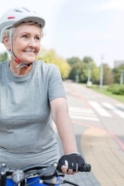 Parkta bisiklet sürme sırasında gülümseyen kadın kıdemli emin
