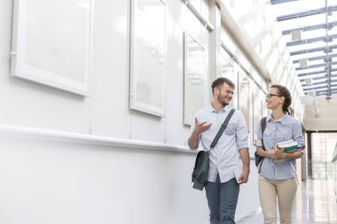 Üniversitesi'nde koridorda yürürken konuşan gülümseyen genç arkadaşlar