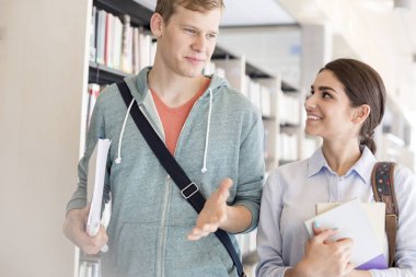 Kitaplık Kütüphane tarafından yürürken arkadaşına konuşan adam