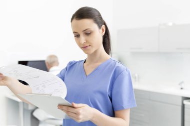 Dişçi kliniğindeki tıbbi belgeleri analiz eden hemşire.