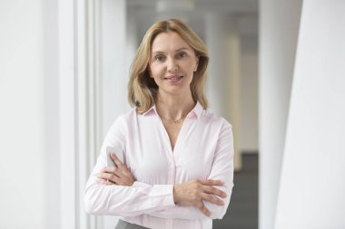 Ofiste koridorda kolları kesişmiş duran kendine güvenen iş kadınının portresi