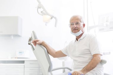 Kendine güvenen üst düzey dişçi Diş Kliniği, sandalye üzerinde oturan portresi