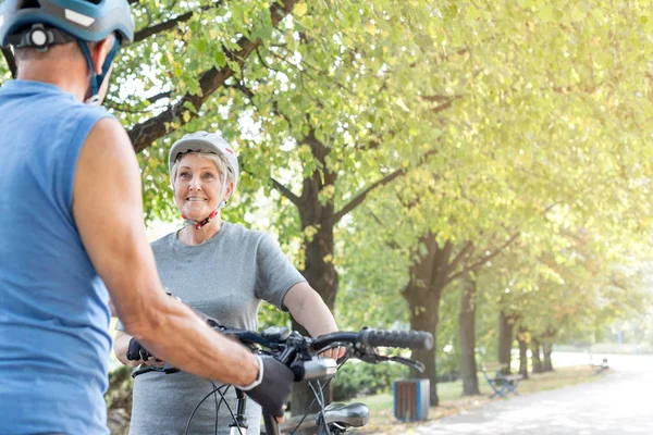 Sorrindo Mulher Sênior Olhando Para Homem Com Bicicleta Parque — Fotografia de Stock