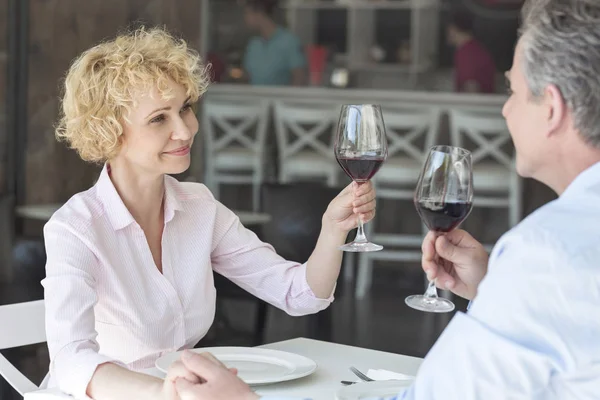 サーフェスは レストランでテーブルに座っている間 笑顔の成熟したカップルを乾杯 — ストック写真