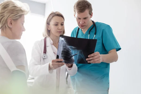 理疗师通过X光对医院护士和病人进行讨论 — 图库照片