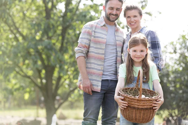 農場でバスケットに卵を持っている女の子と立っている両親 — ストック写真