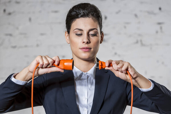 Confident businesswoman attaching red cables against brick wall