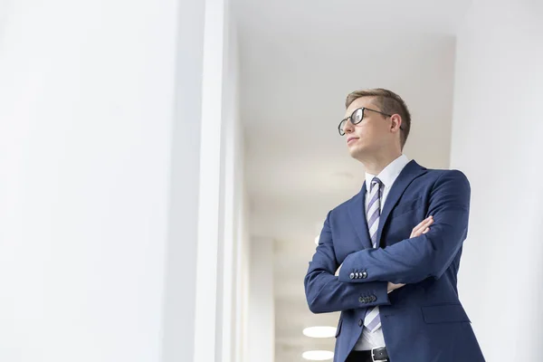 Young Thoughtful Businessman Standing Arms Crossed Looking Away Office Corridor — Stock Photo, Image