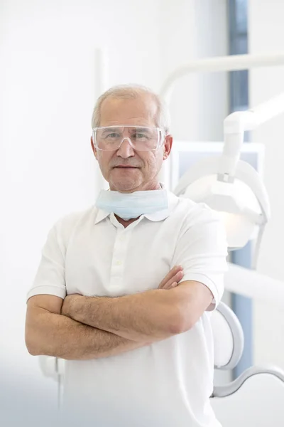 自信的牙医的肖像与胳膊横渡在牙科诊所 — 图库照片