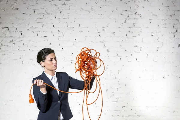 Zelfverzekerde Jonge Zakenvrouw Kijken Naar Verwarde Rode Kabel Tegen Witte — Stockfoto