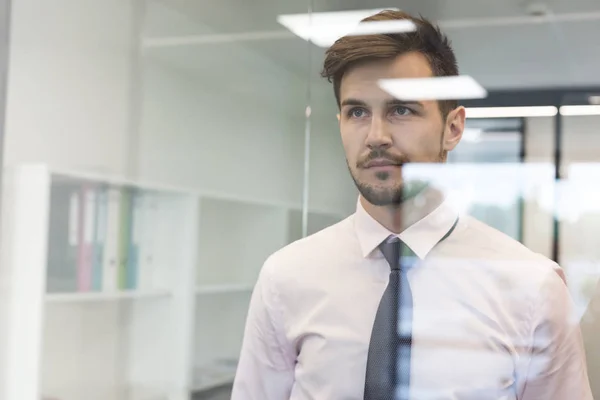 Nachdenklicher Geschäftsmann Blickt Durch Glasfenster Ins Büro — Stockfoto
