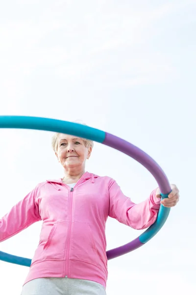 Lage Hoekmening Van Senior Vrouw Uitoefenend Met Hoelahoep Tegen Hemel — Stockfoto