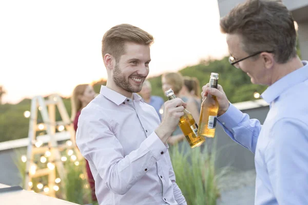 テラスでの成功パーティー中にビールでボトルを乾杯する2人のビジネスマン — ストック写真