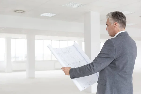 Reifer Geschäftsmann Betrachtet Entwurf Während Neuem Leerem Büro Steht — Stockfoto