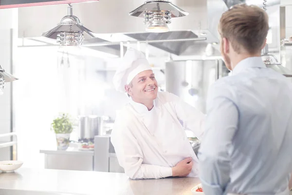 Chef Mature Souriant Parlant Avec Jeune Serveur Comptoir Cuisine Restaurant — Photo