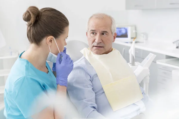 Стоматолог Разговаривает Удивленным Пожилым Пациентом Сидящим Стоматологической Клинике — стоковое фото