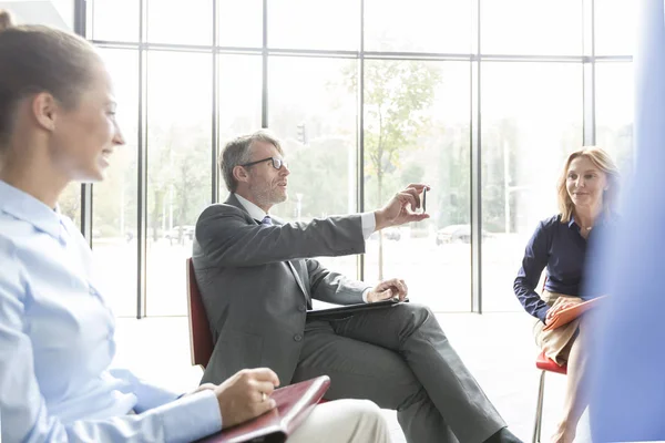 Empresario Mostrando Teléfono Inteligente Sus Colegas Mientras Planea Durante Reunión — Foto de Stock