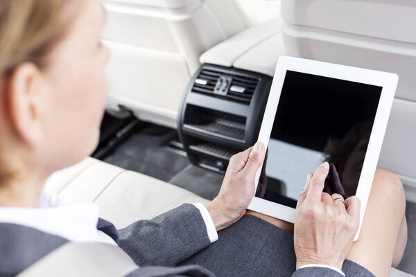 Businesswoman using digital tablet in car during trip