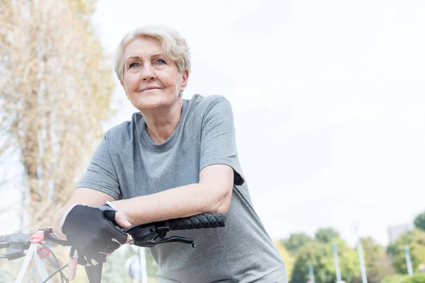 Confident Senior Woman Leaning Bicycle Handlebar Park — Stock Photo, Image