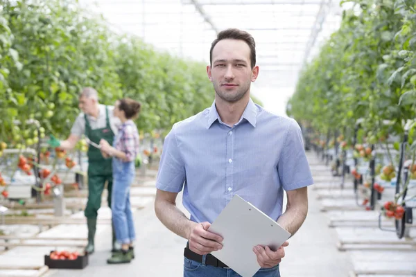 Portret Van Toezichthouder Met Klembord Staan Tegen Boeren Broeikasgassen — Stockfoto