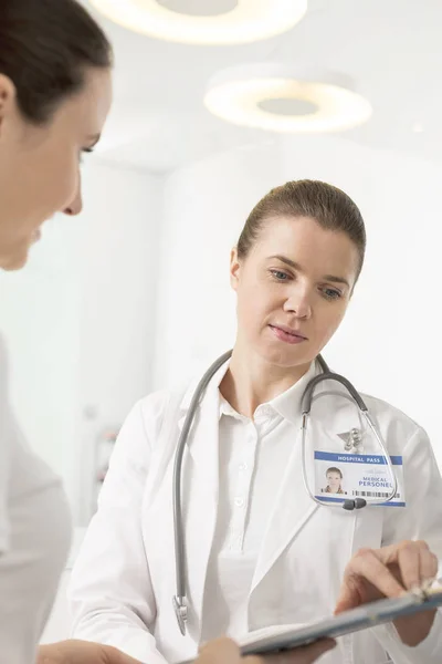 Doctora Discutiendo Con Asistente Sobre Portapapeles Hospital —  Fotos de Stock