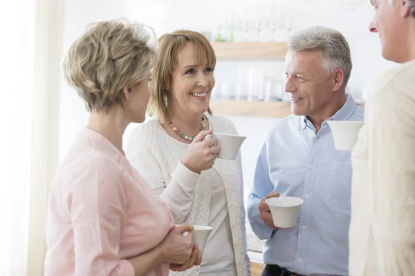 Sorrindo Amigos Maduros Segurando Bebidas Enquanto Conversava Sala Estar Casa — Fotografia de Stock