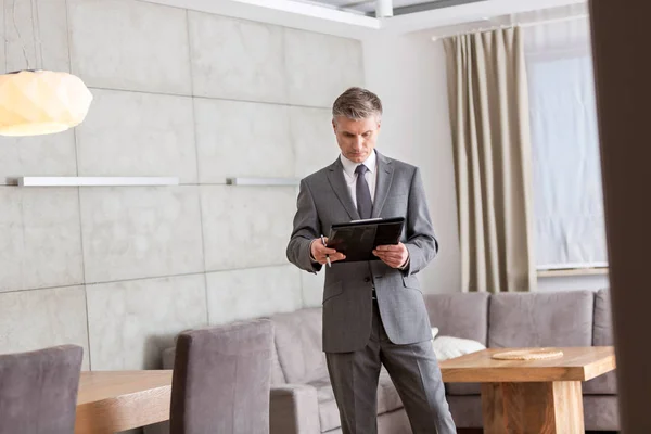 Confident Mature Male Realtor Reading Document While Standing Home — Stock Photo, Image