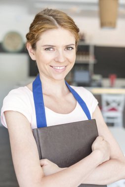 Restoranda menü holding ile ayakta gülümseyen genç garson portresi