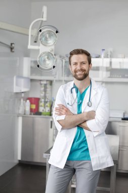 Klinikte kolları çapraz gülümseyen veteriner doktor portresi