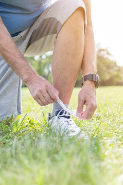 Düşük bölümü kıdemli koşucu çimenli sahada bağcık bağlama