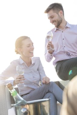 Genç iş arkadaşları çatıda başarı partisinde otururken konuşuyor