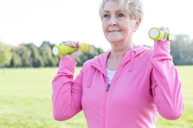 Parkta egzersiz dumbbells ile aktif kadın kıdemli