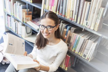 Kadın otururken karşı bookshelf Kütüphanesi'nde kitap okuma portresi