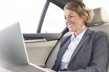 Gülümseyen iş kadını arabaya dizüstü bilgisayar kullanarak 