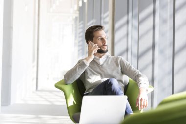 Ofisinde sandalyede otururken cep telefonu üzerinde konuşurken işadamı