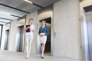 Asansör ofis lobisinde üzerinden yürürken konuşmak iş kadınları
