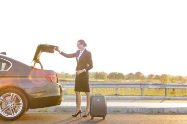 Genç iş profesyonel gökyüzü karşı yolda araba bagajı bavul kaldırılıyor 