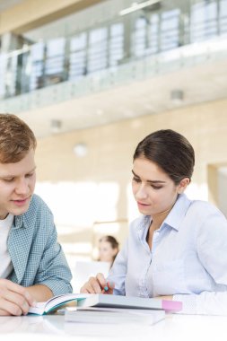 Arkadaşlar kitabı üzerinde birlikte Üniversite Kütüphanesi masada otururken tartışırken