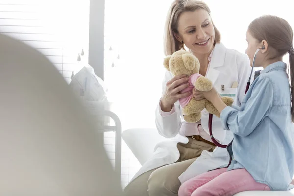 病院で女の子にテディベアを与える笑顔の医者 — ストック写真