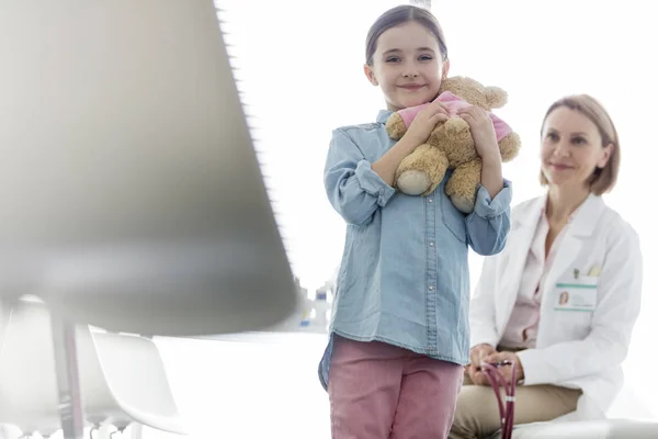 Porträtt Leende Flicka Som Innehar Teddybear Medan Läkare Sitter Sjukhuset — Stockfoto