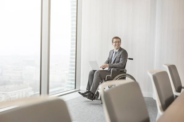 現代のオフィスの会議室でラップトップを持つ笑顔の障害者ビジネスマン — ストック写真
