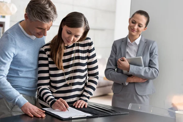 Glimlachende Jonge Verkoper Kijken Naar Vrouw Ondertekening Contract Terwijl Staande — Stockfoto