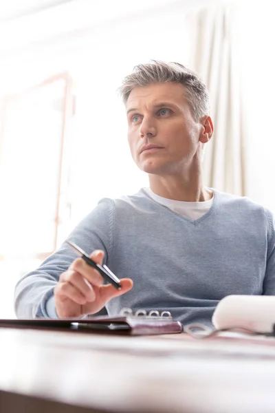 Nachdenklicher Reifer Mann Sitzt Mit Dokument Tisch Und Schaut Wohnung — Stockfoto