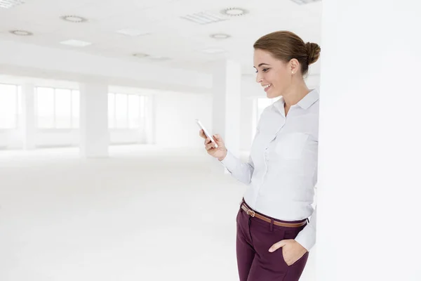 Smiling Young Businesswoman Using Smartphone While Standing New Empty Office — Stock Photo, Image