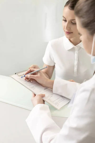 Doctor Filling Form While Discussing Assistant Checkout Counter Clinic — Stock Photo, Image