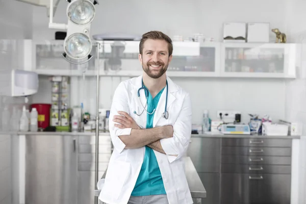獣医クリニックで腕を組んで立っている笑顔の医者の肖像画 — ストック写真