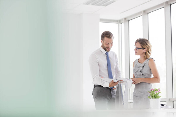 Бизнесмен и предпринимательница обсуждают документы в новом офисе
