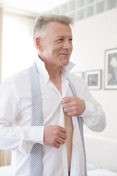 Lächelnder Geschäftsmann Knöpft Hemd Während Hause Schlafzimmer Wegschaut — Stockfoto